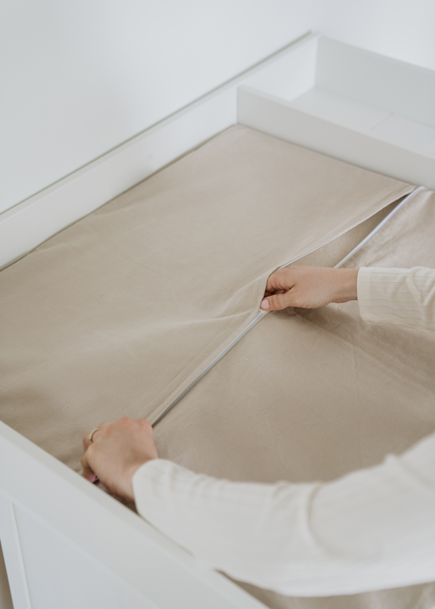 Schließbarer Kissenbezug für die Wickelauflage Eine Frau verschließt den Bezug für die Wickelauflage von Limmaland