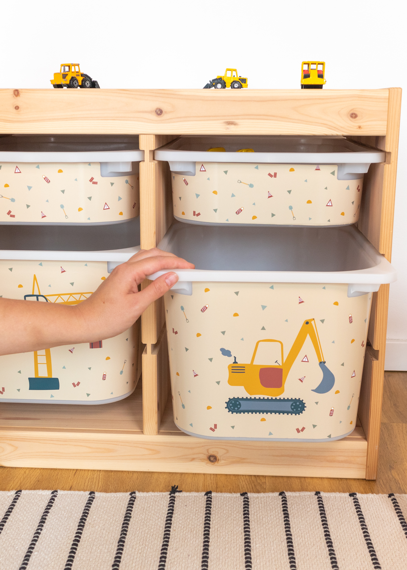 Aufbewahrungsbox im IKEA TROFAST Regal mit gelbem Bagger-Motiv.
