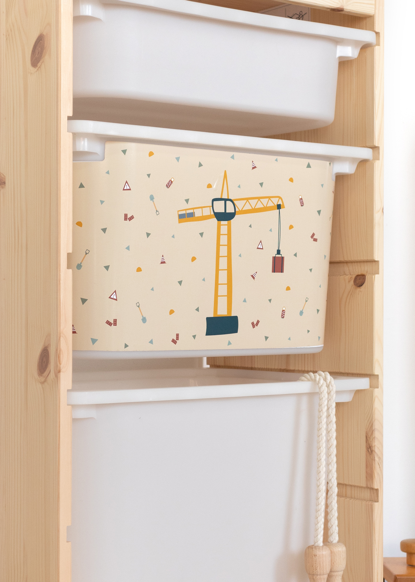 Aufbewahrungsbox im IKEA TROFAST Regal mit farbigem Kran-Muster für Kinder.