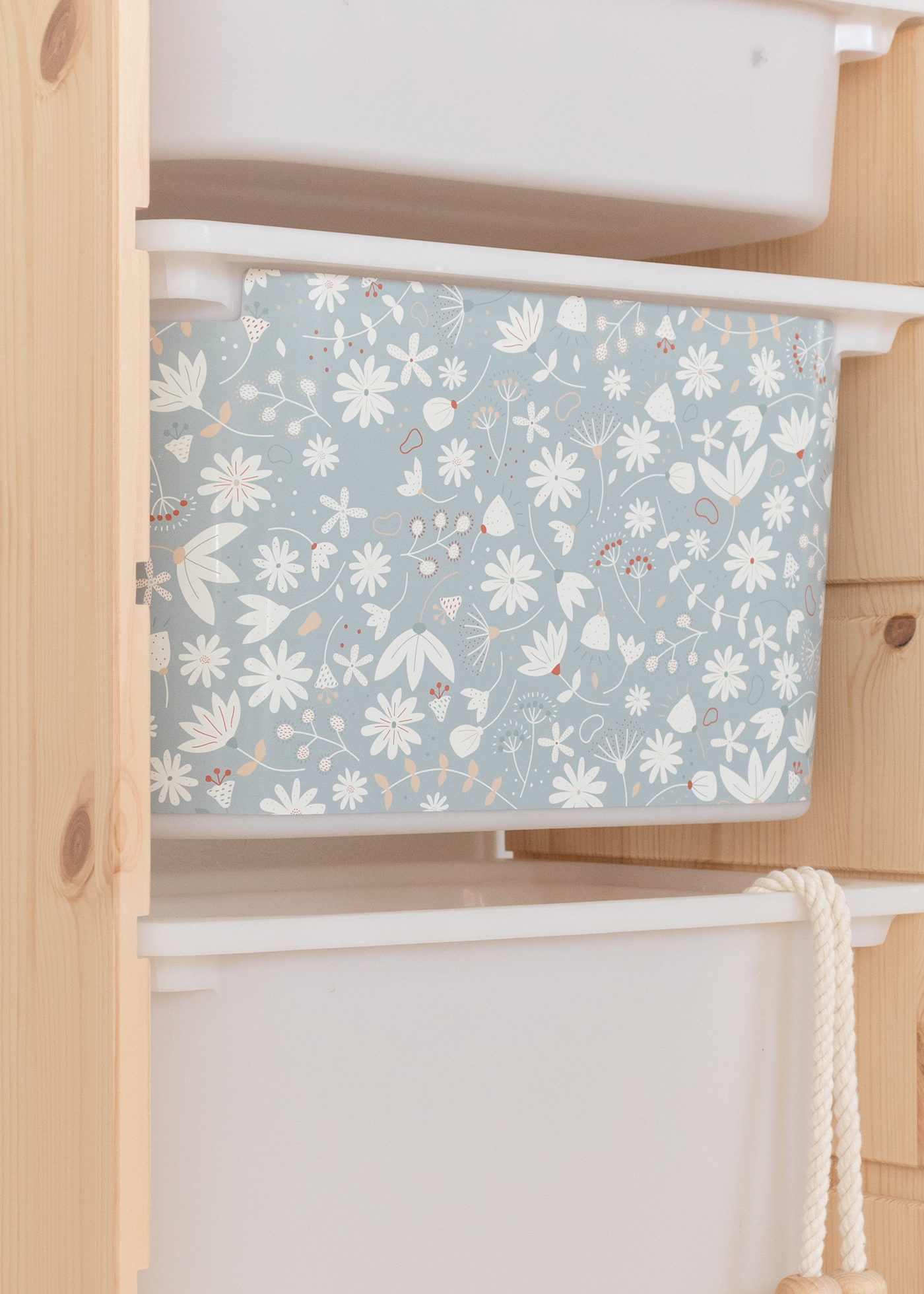 Aufbewahrungsbox im IKEA TROFAST Regal, verziert mit einem verspielten grünen Blumenmuster.
