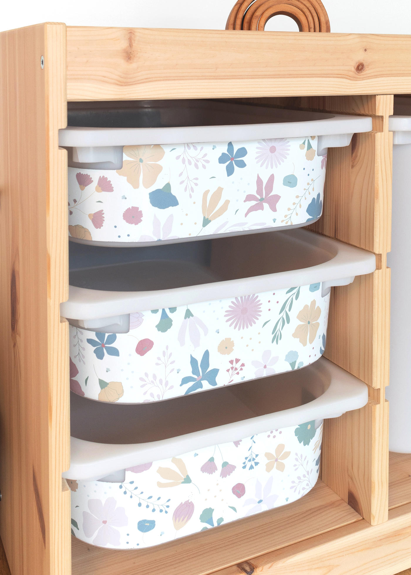 IKEA TROFAST Boxen mit bunten Blumenmotiven Ein IKEA TROFAST Regal im Zimmer, geschmückt mit einer Blumenmuster-Möbelfolie.