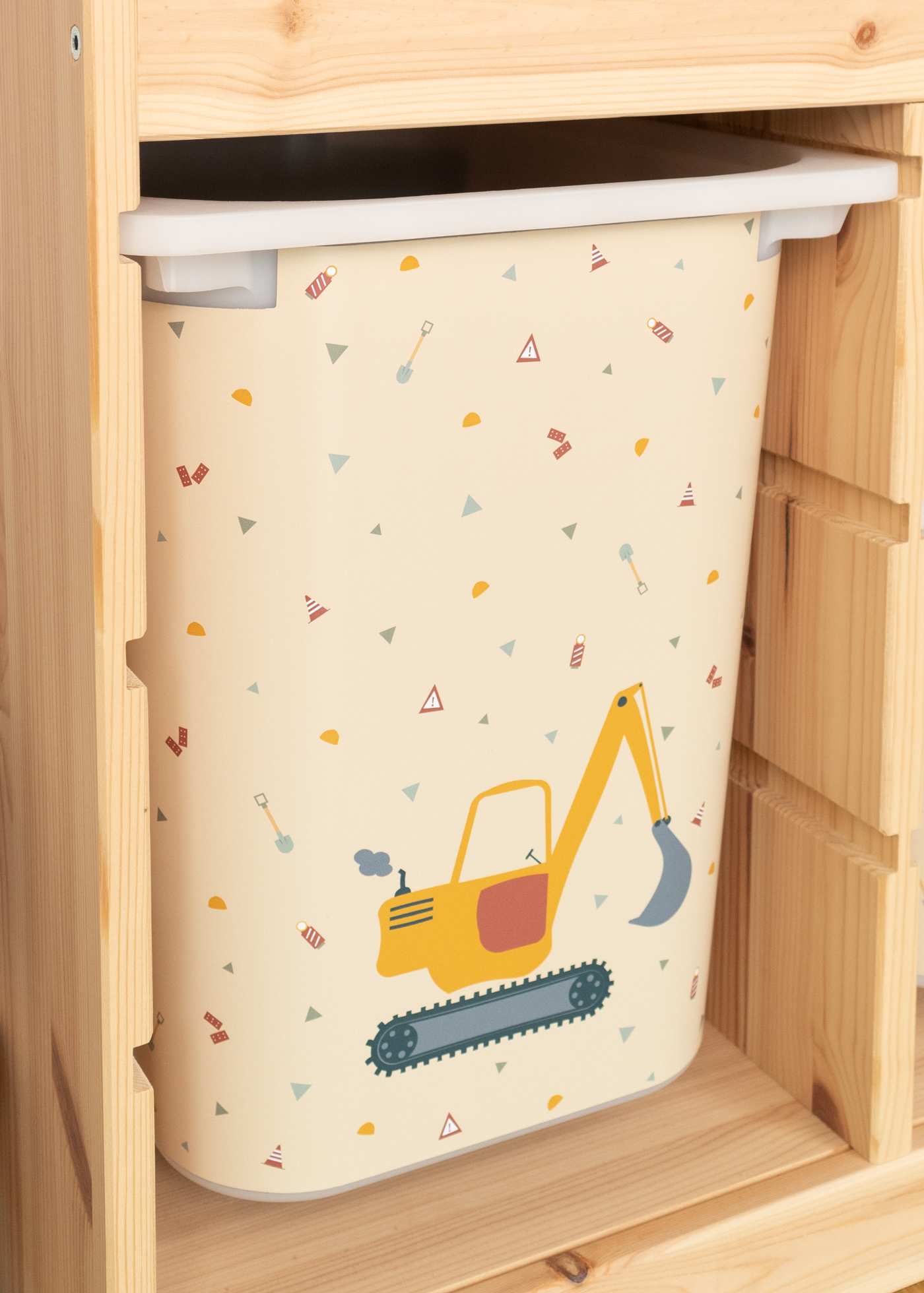 Gelber Bagger auf Aufbewahrungsbox Gelbes Bagger-Motiv auf beiger Box im IKEA TROFAST Regal.
