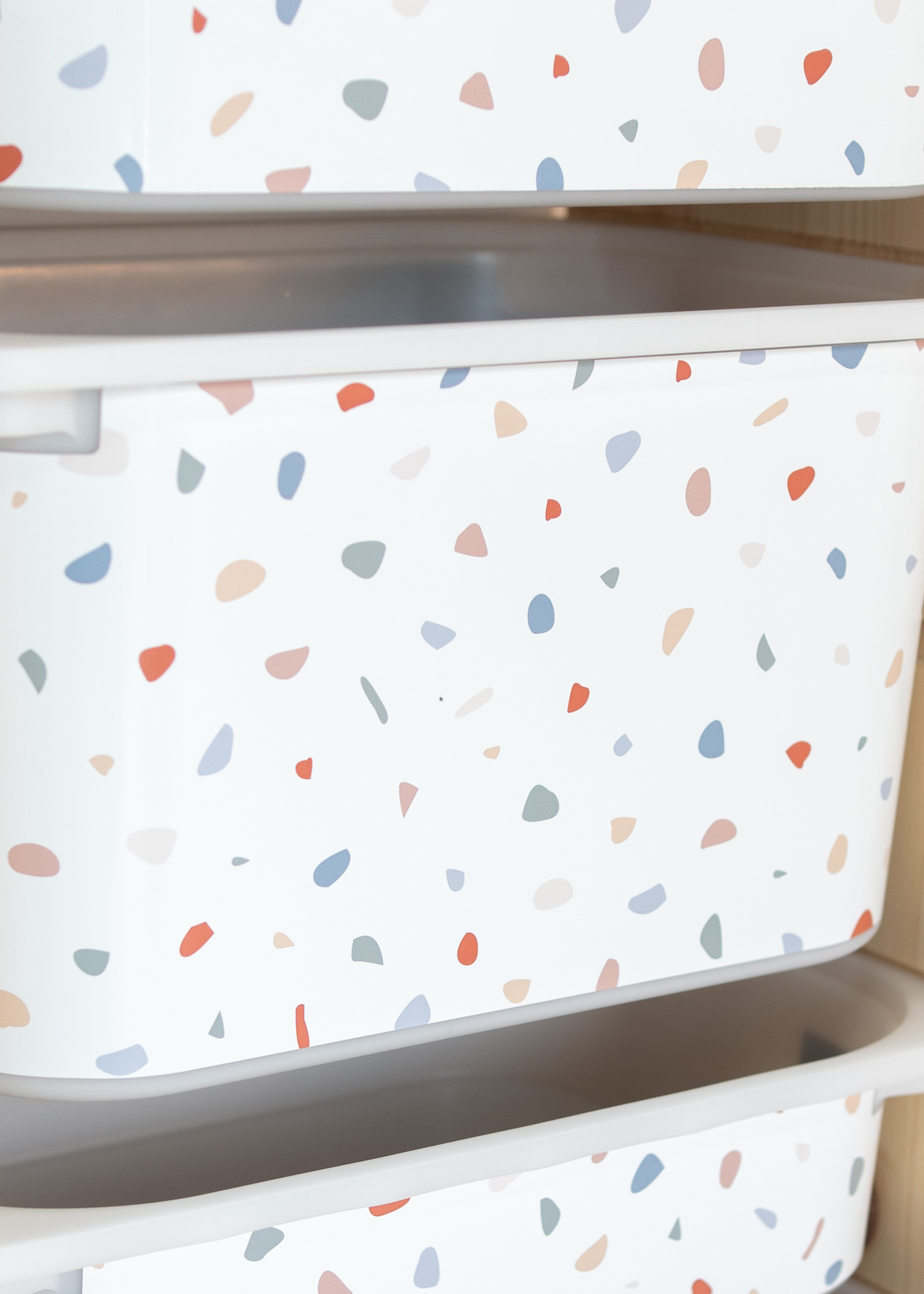 Aufbewahrungsbox im IKEA TROFAST Regal, dekoriert mit einer Klebefolie im bunten Terrazzo-Design.