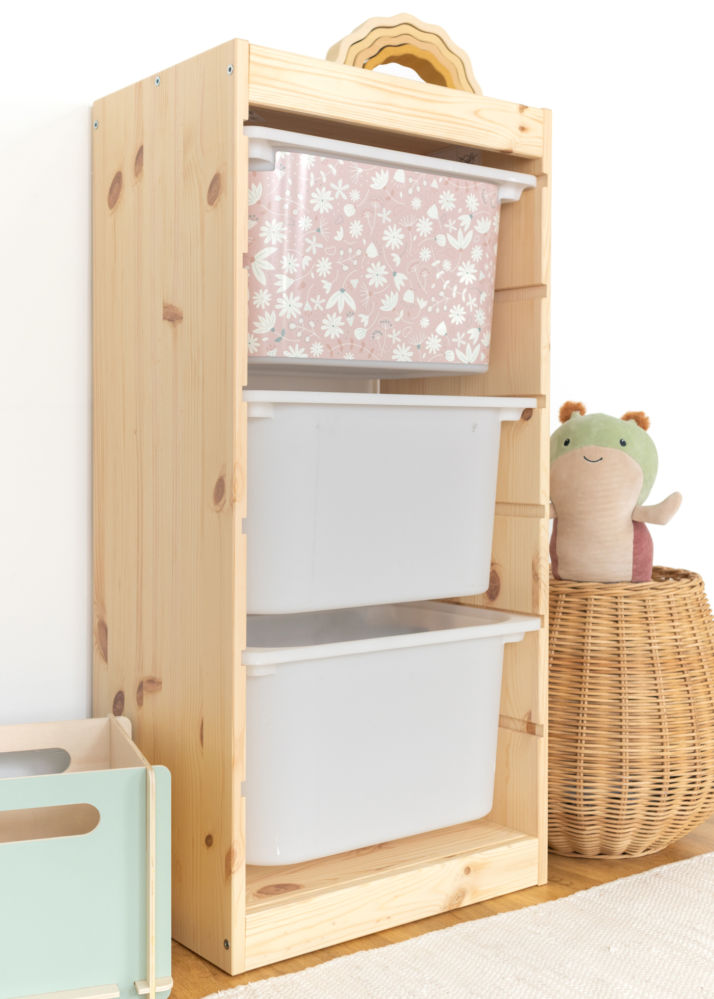 Dekorative Box mit rosa Blumenmuster im TROFAST Regalsystem Aufbewahrungsbox im IKEA TROFAST Regal mit einem weichen rosa Blumenmuster, ideal für Kinderzimmer.