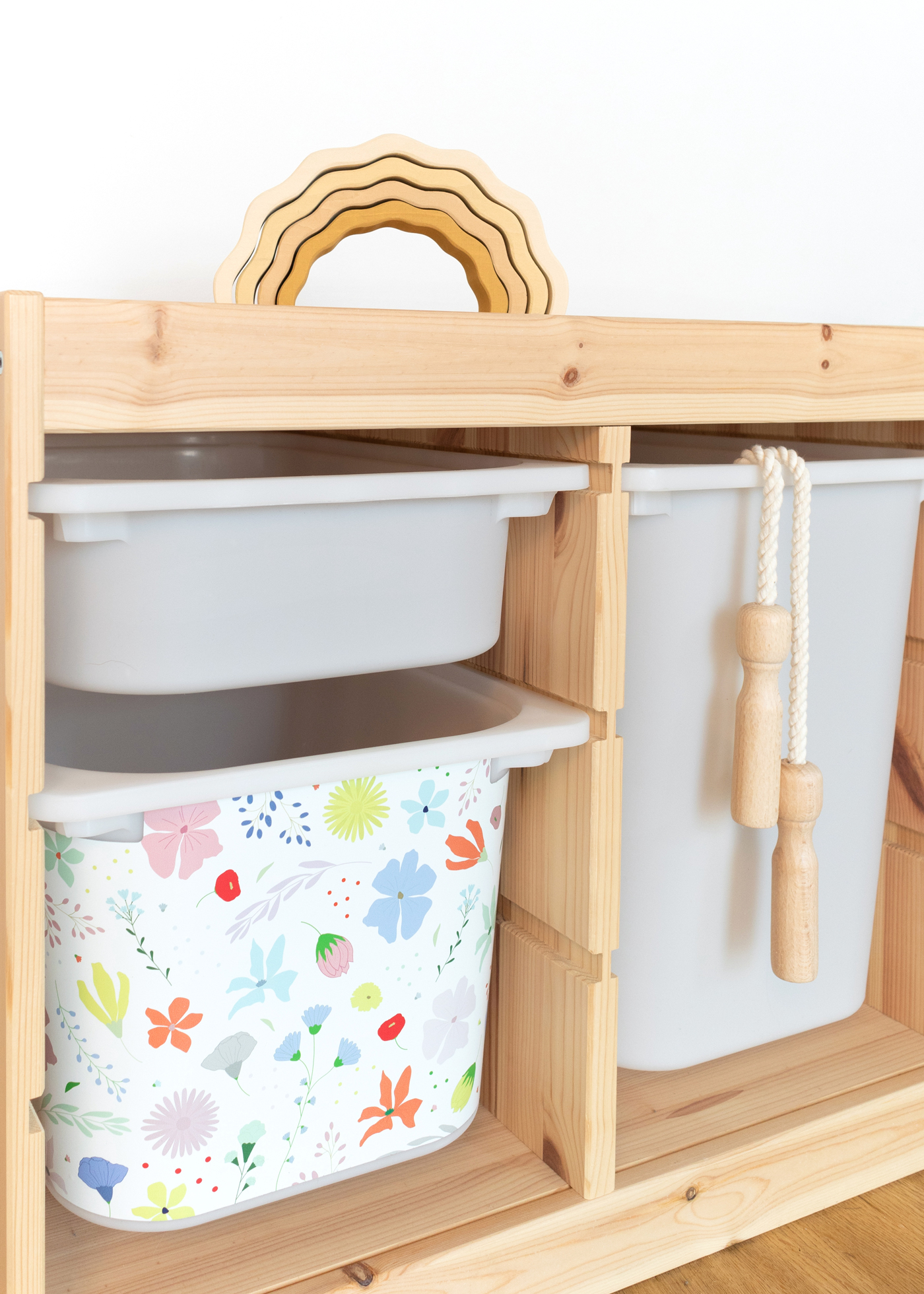 Klebefolie für IKEA TROFAST Ein IKEA TROFAST Regal im Zimmer, verziert mit einer bunten Blumenmuster-Möbelfolie.