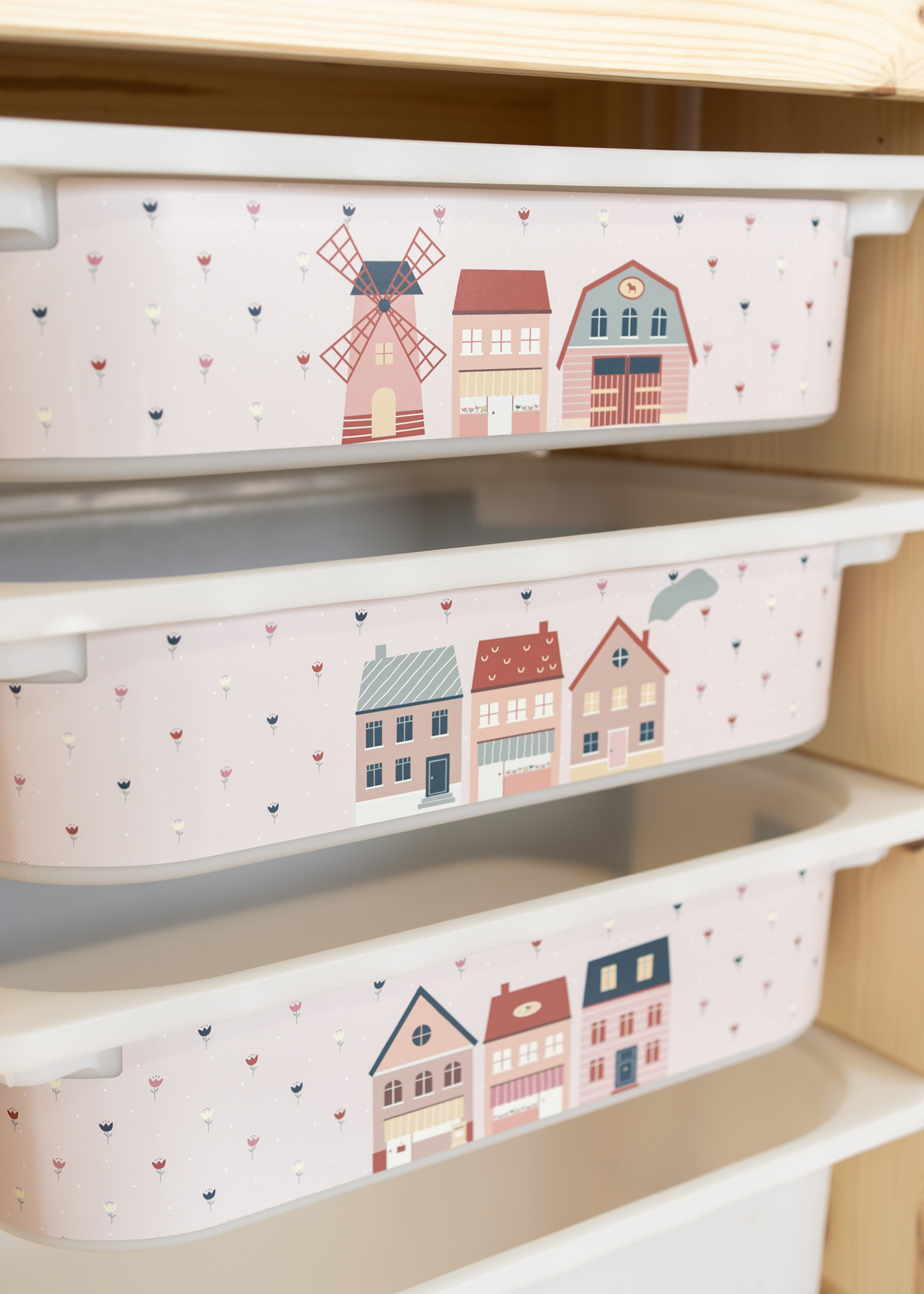 Rosa Aufbewahrungsbox im IKEA TROFAST Regal mit einer bunten Dorf-Szene.