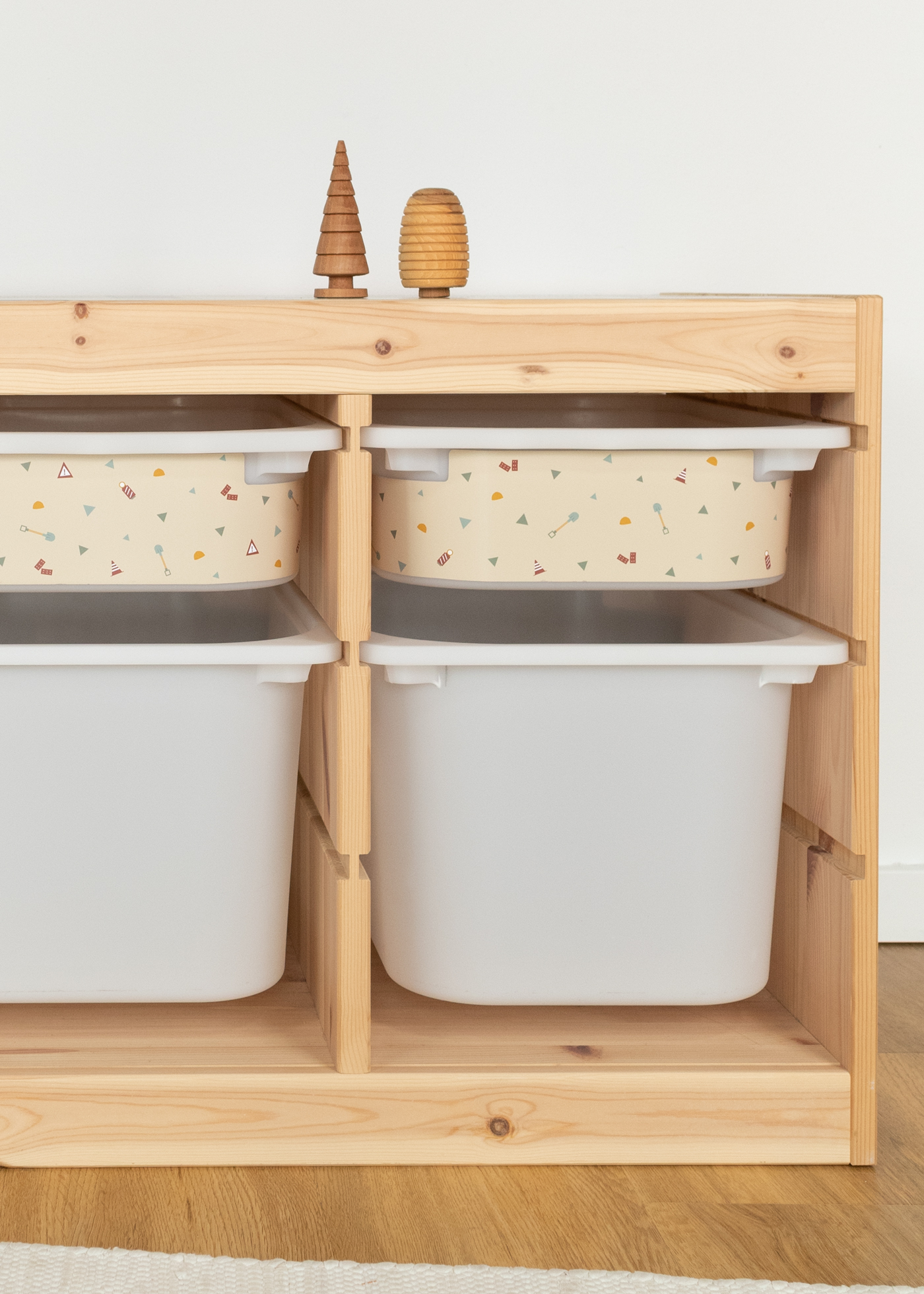 Kleine beige Aufbewahrungsbox im IKEA TROFAST Regal mit Baustellen-Motiven, darunter eine große weiße Box zur zusätzlichen Aufbewahrung.