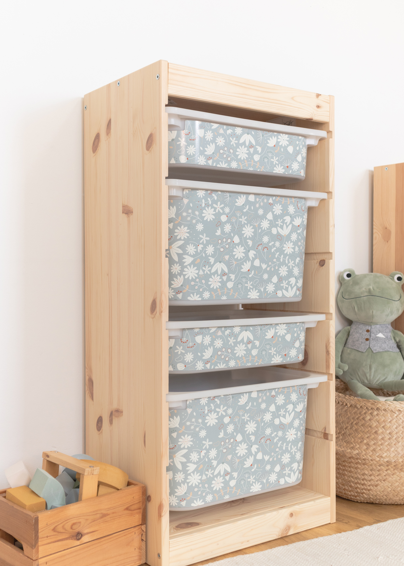 Aufbewahrungsbox mit grünem Blumen-Design im IKEA TROFAST Regal Kindgerechte Aufbewahrungsbox im TROFAST Regal, dekoriert mit einem grünen Blumenmuster.