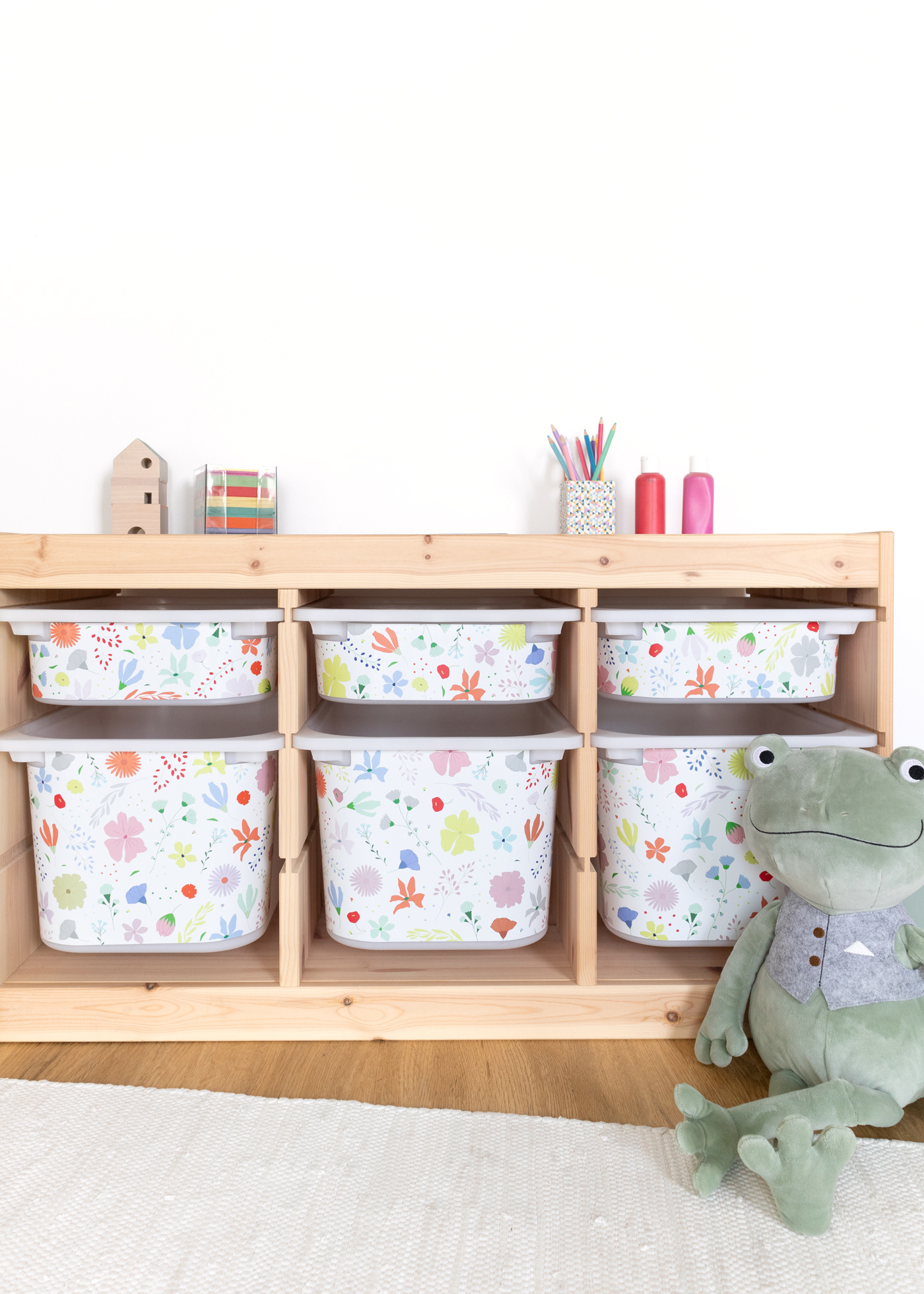 Selbstklebende Möbelfolie mit Blumenmuster für IKEA TROFAST Ein IKEA TROFAST Regal im Zimmer, verziert mit einer farbenfrohen Blumenmuster-Klebefolie