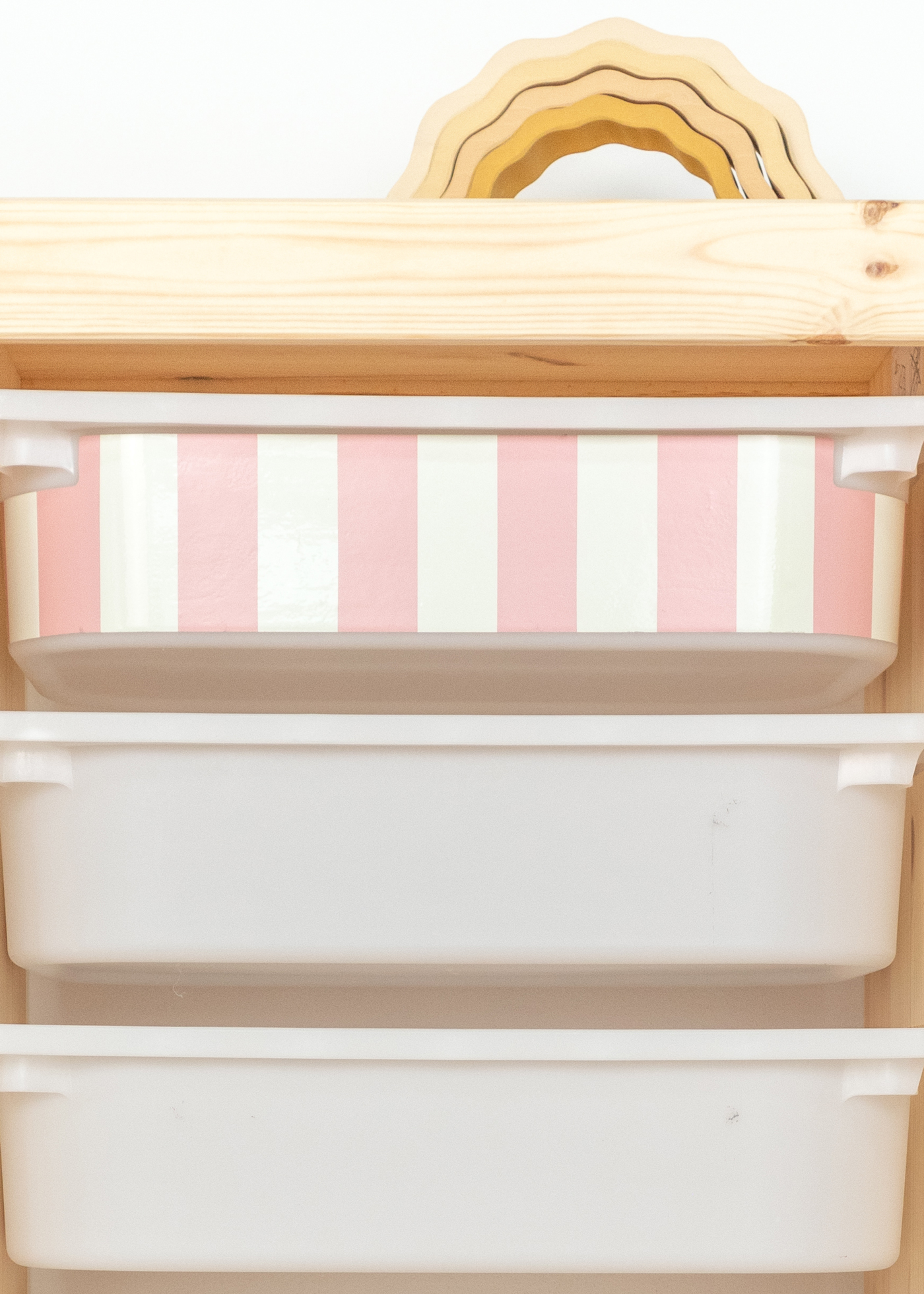 Aufbewahrungsbox im IKEA TROFAST Regal mit einem weichen rosa-gestreiften Muster. Dekorative Box mit rosa Streifenmuster im TROFAST Regalsystem