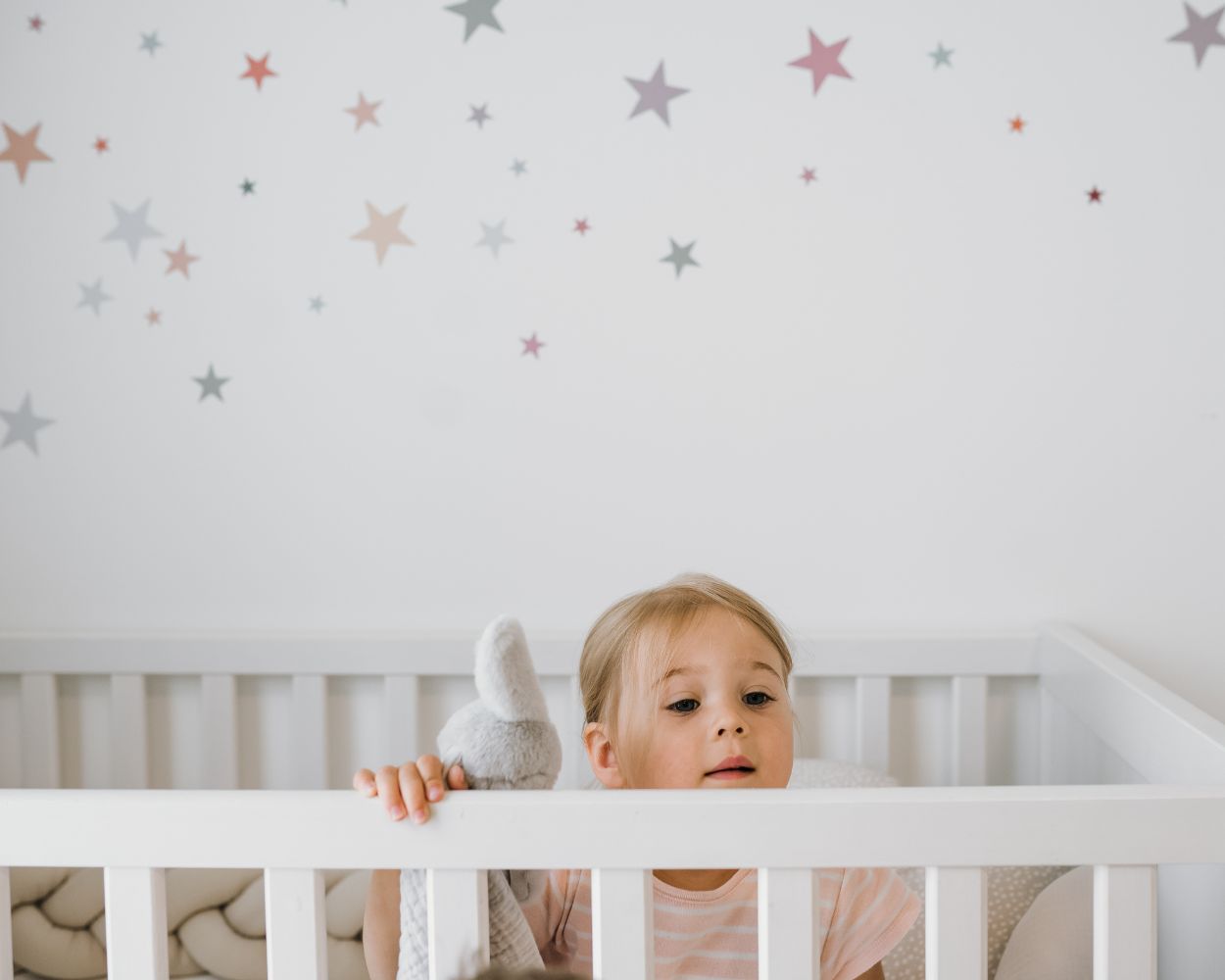 Mädchen im IKEA Babybett mit Wandtattoos Sterne Mädchen im IKEA Babybett mit Wandtattoos Sterne