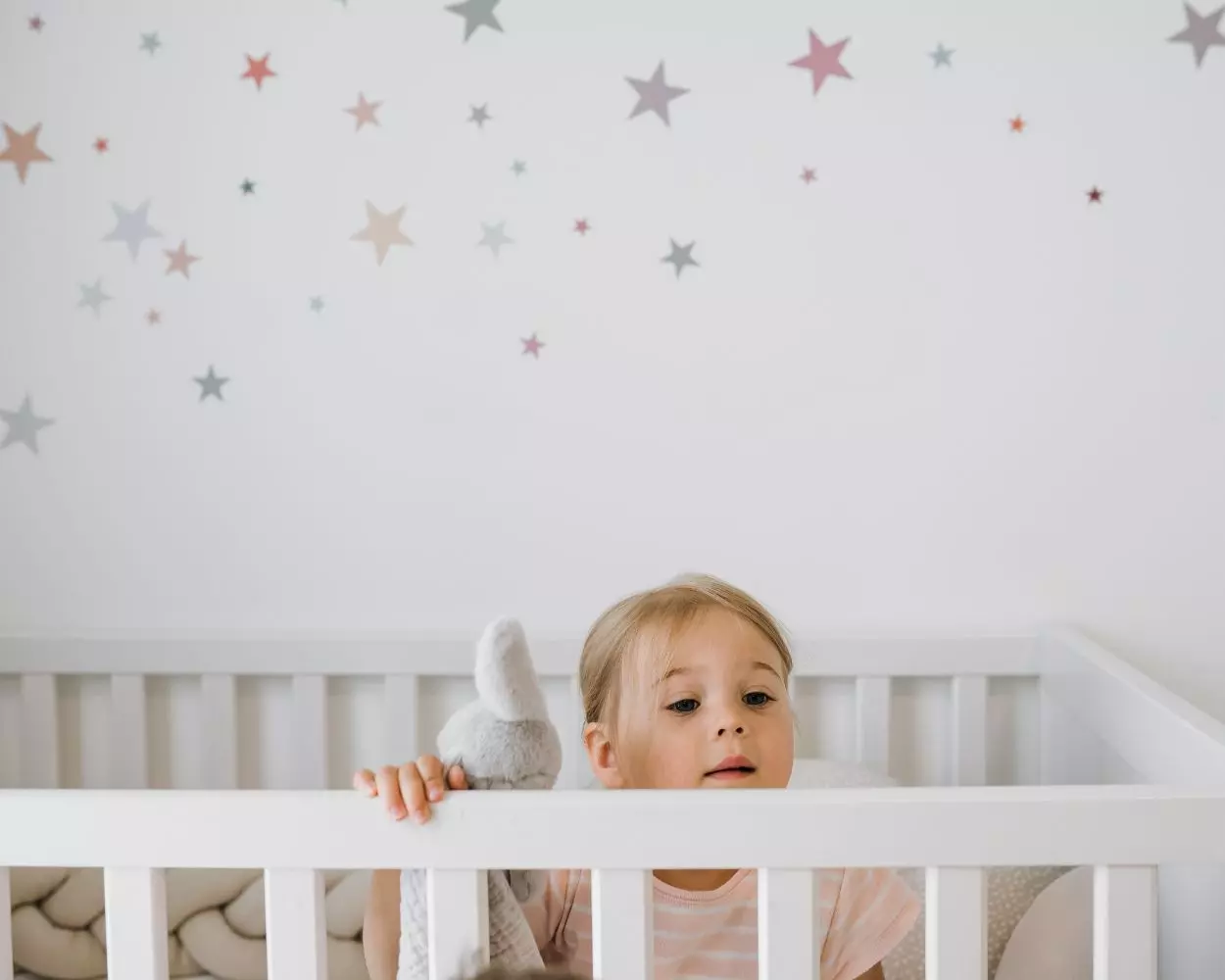 Mädchen im IKEA Babybett mit Wandtattoos Sterne