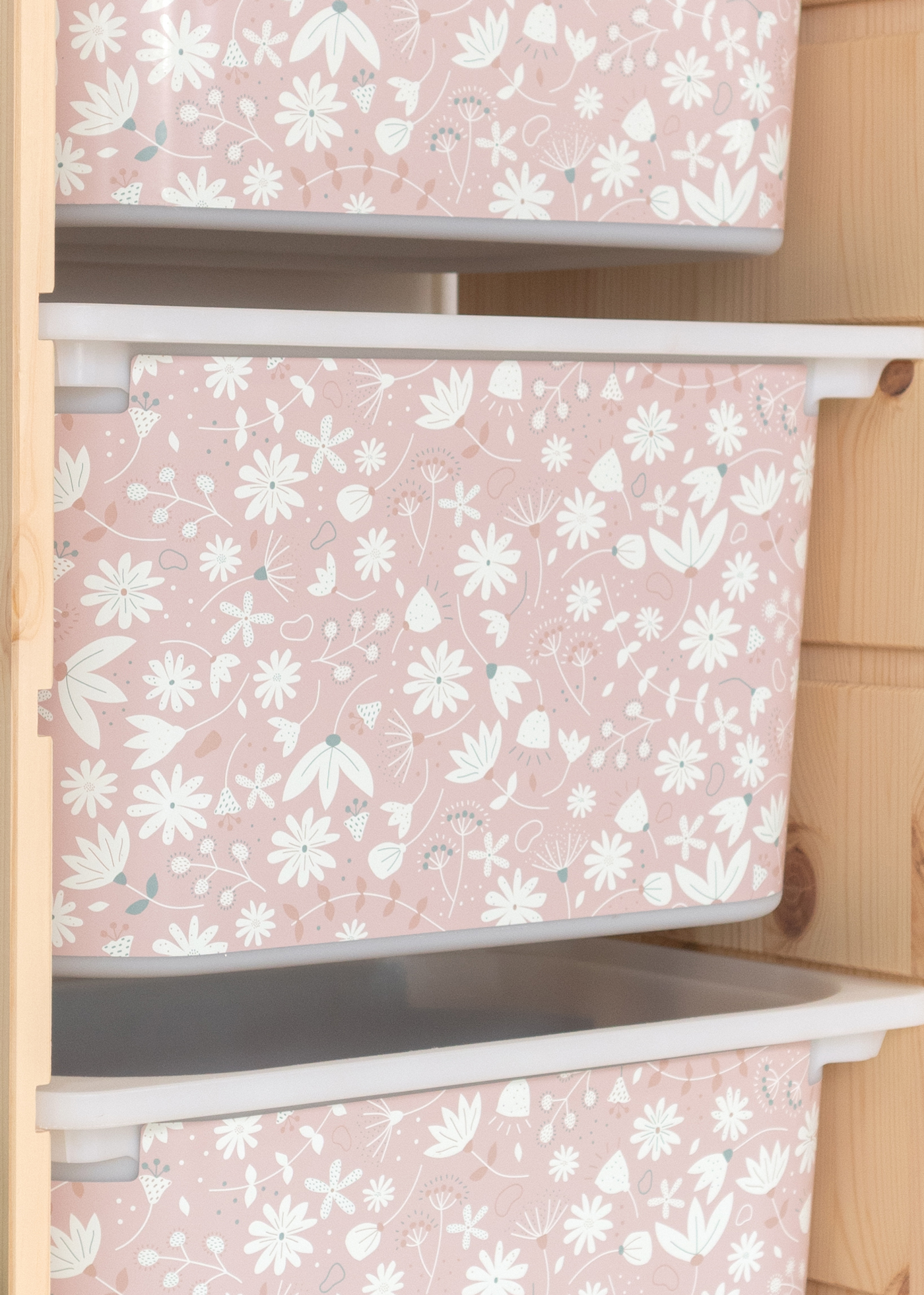 Aufbewahrungsbox im IKEA TROFAST Regal, bedruckt mit einem zarten rosa Blumenmotiv.