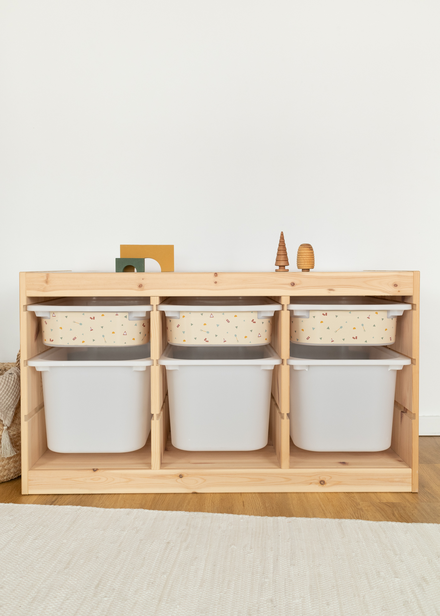 Dekorative Baustellen-Musterbox im IKEA TROFAST Regal Seitlicher Blick auf ein IKEA TROFAST Regal mit einer kleinen Aufbewahrungsbox, beklebt mit Bagger-, Kran- und Kipplader-Motiven und einer schlichten weißen Box darunter.