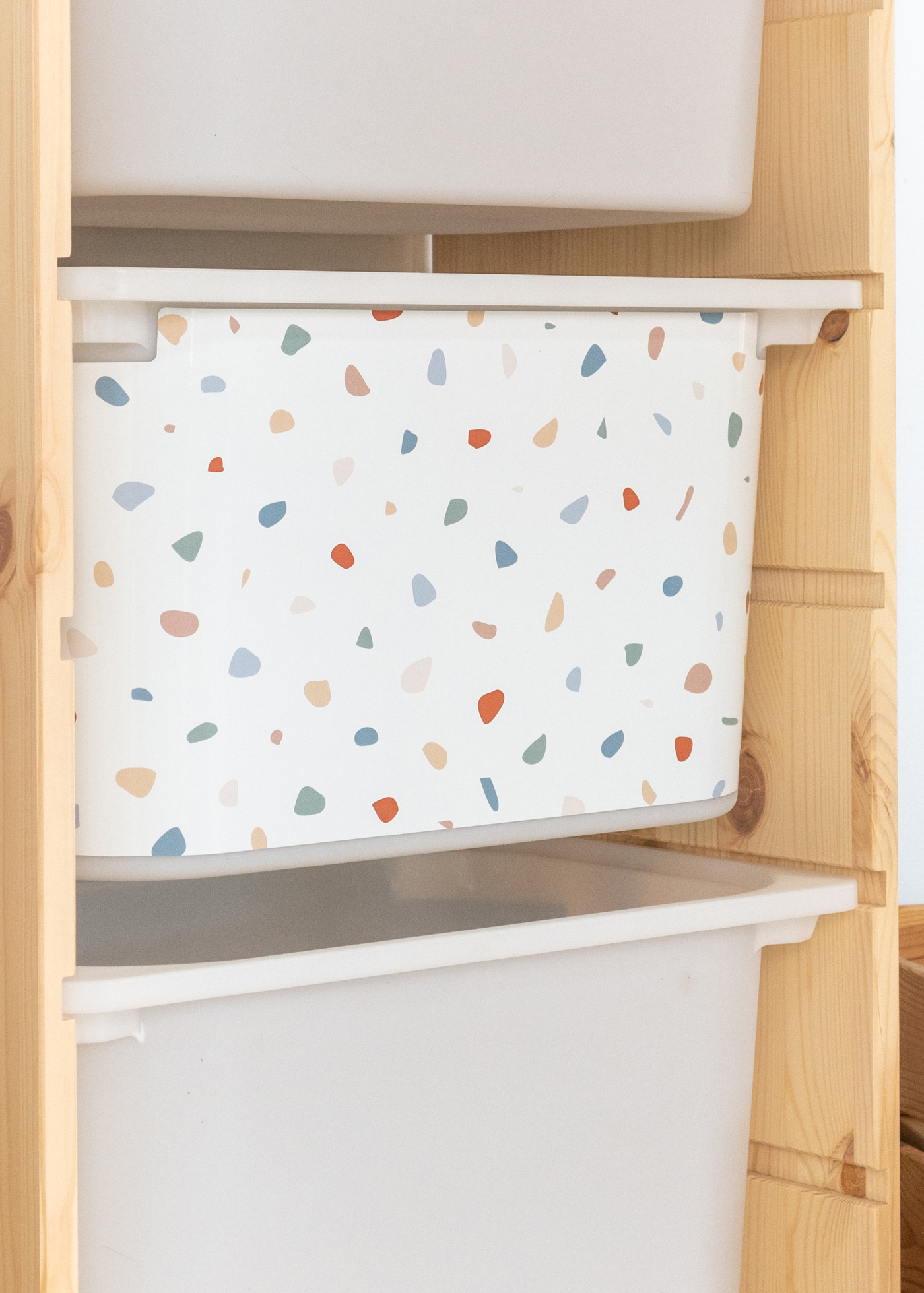 Kinder-Aufbewahrung mit Terrazzo-Klebefolie im TROFAST Regal IKEA TROFAST Regal mit bunter Terrazzo-Klebefolie auf der Aufbewahrungsbox, ideal für das Kinderzimmer.