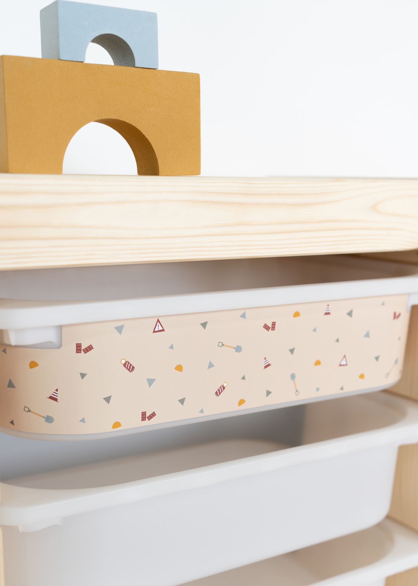 Aufbewahrungsbox mit Baustellenmotiven im IKEA Regal Praktische beige Box im IKEA TROFAST Regal mit Bagger, Kran und Kipplader als Dekor.