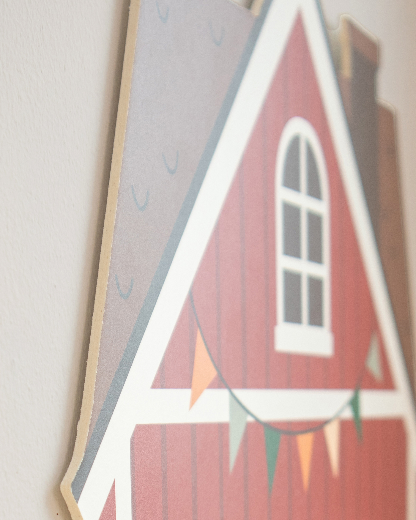 Holzschild, Hausform, rote Fassade, Fenster, Girlanden
