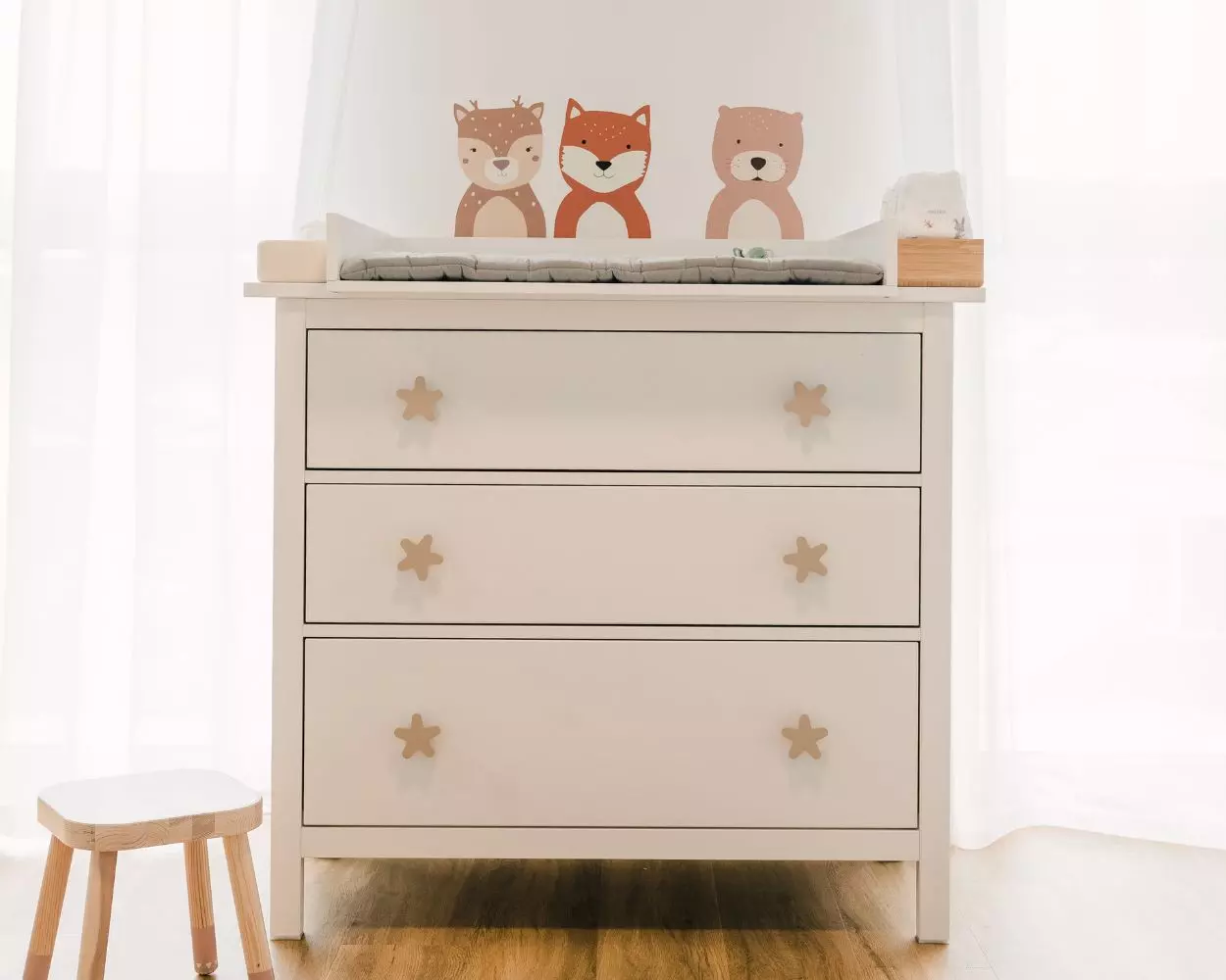 Wickelkommode im Babyzimmer mit Wandstickern und Möbelgriffen