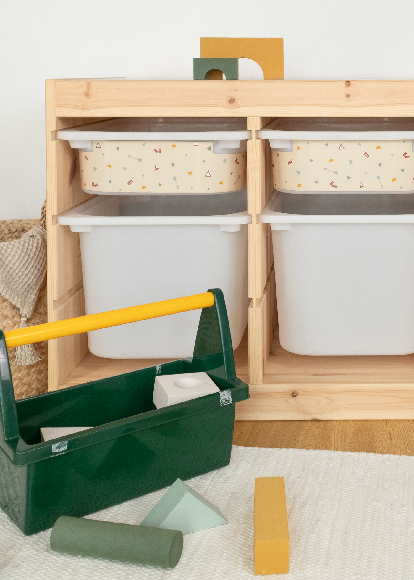Praktische Aufbewahrung im IKEA TROFAST Regal mit einer beige Box, bedruckt mit bunten Bagger-, Kran- und Kipplader-Motiven.
